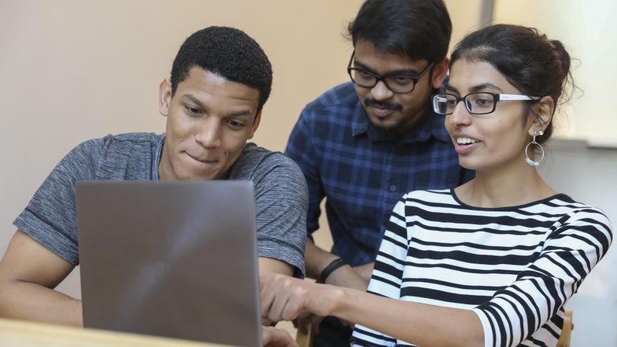 Internationale Studierende schauen gemeinsam auf einen Laptop 